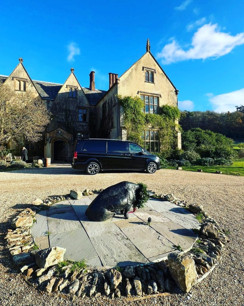 black hilton ames vehicle outside country home with statue