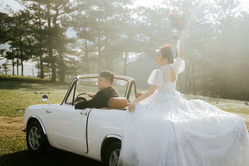 A couple celebrating their wedding in a vintage convertible car outdoors.
