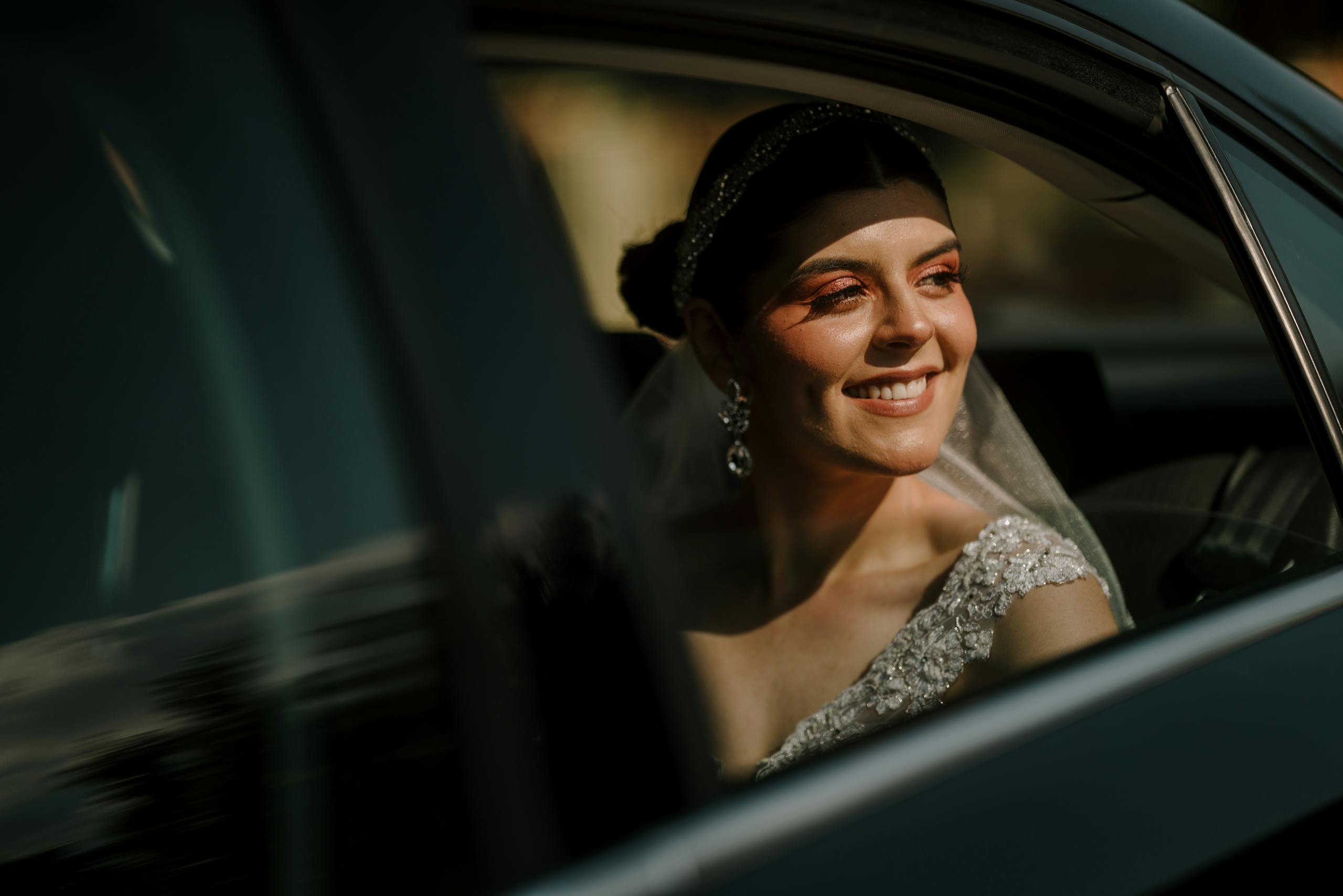 Radiant bride smiling from limousine window, capturing a joyful wedding moment.